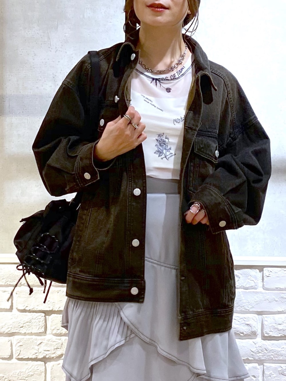 ブラック系のデニムジャケット、グレー系のスカート、ブラック系のスニーカーを着用したレディースの春コーディネートの2枚目の写真