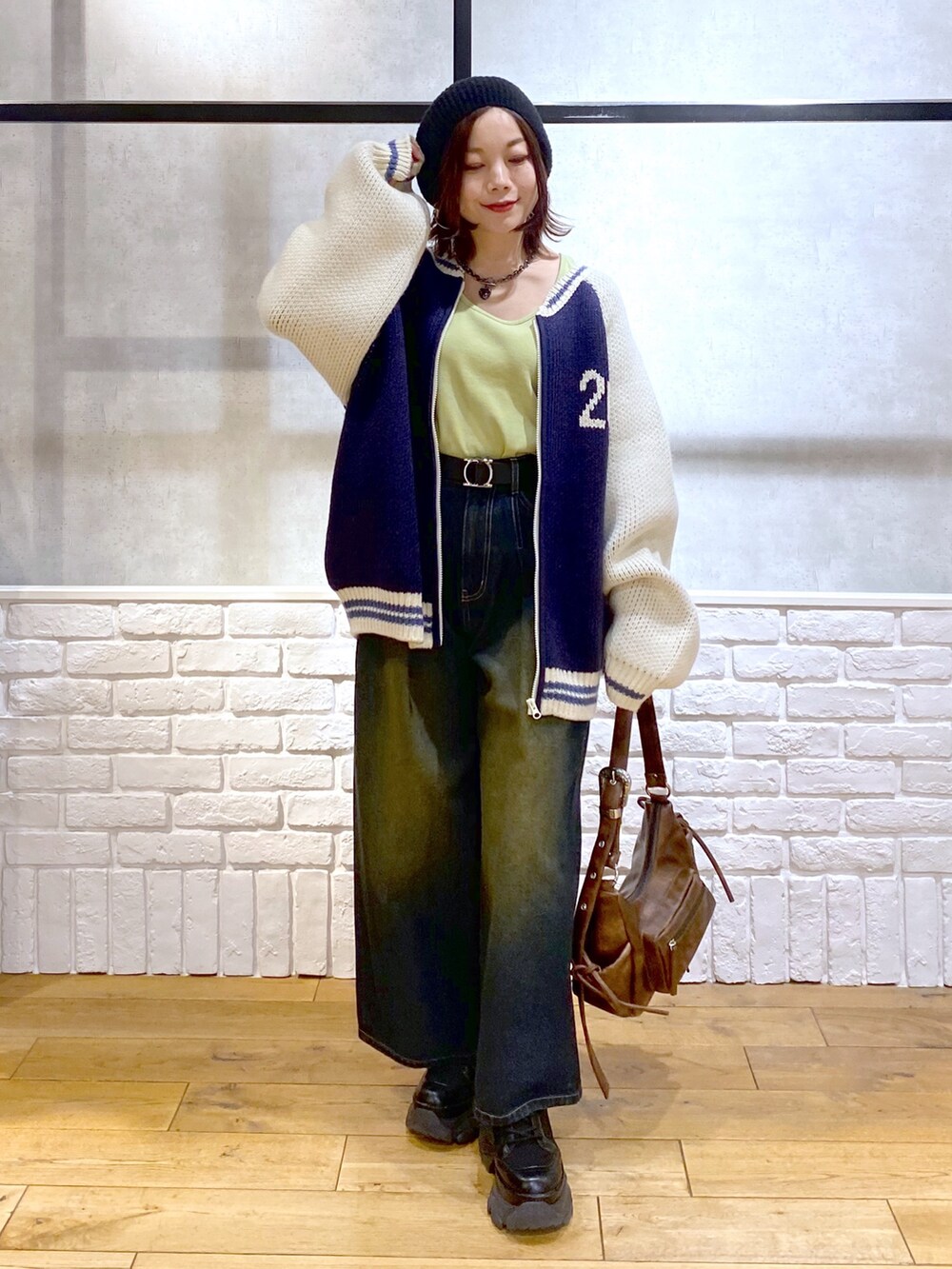 イエロー系のTシャツ/カットソー、ブラウン系のショルダーバッグ、ブルー系のデニムパンツを着用したレディースの冬コーディネートの9枚目の写真