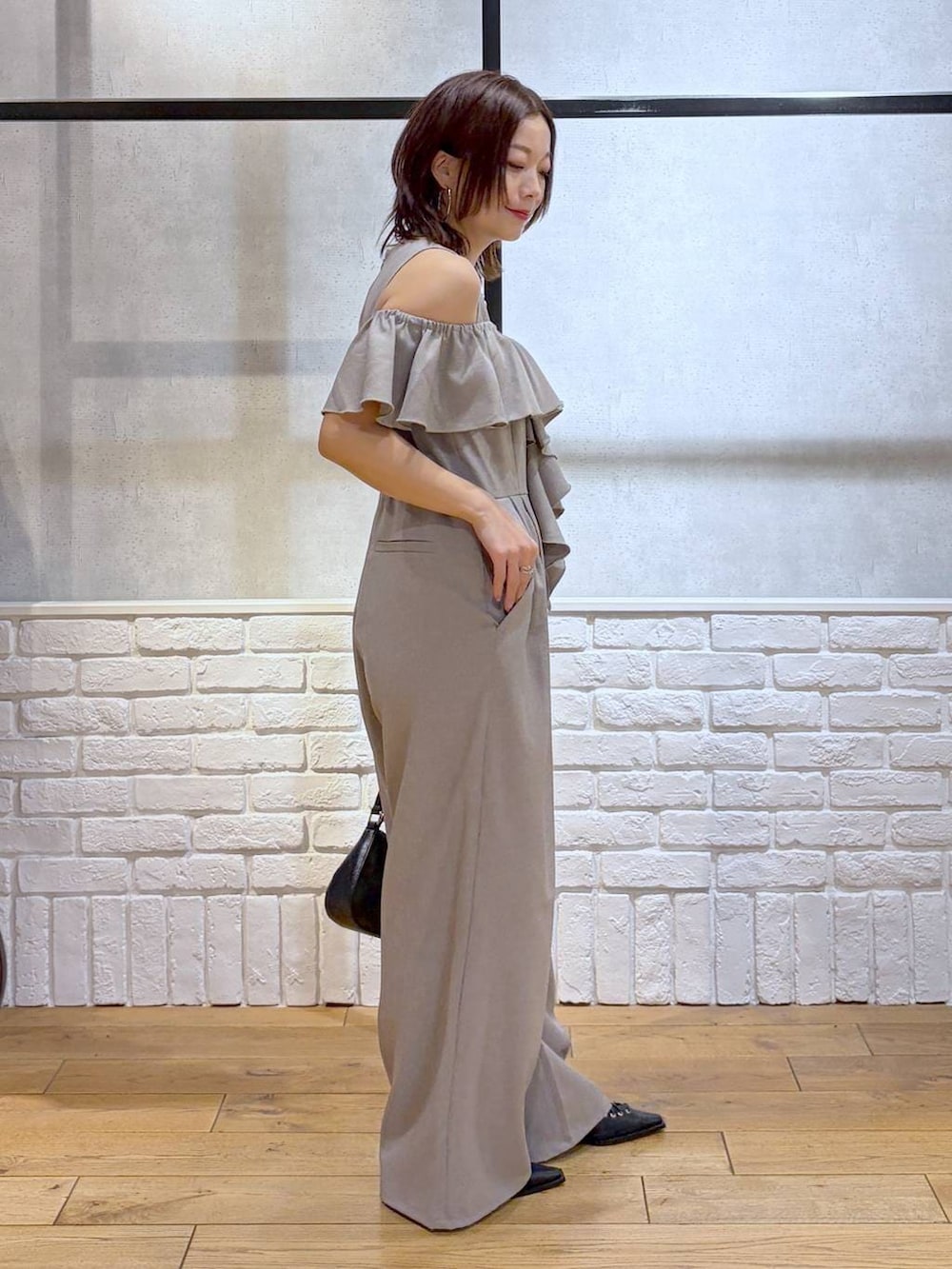 ブラック系のハンドバッグ、ブラック系のサンダル、ベージュ系のサロペット/オーバーオールを着用したレディースの春コーディネートの3枚目の写真