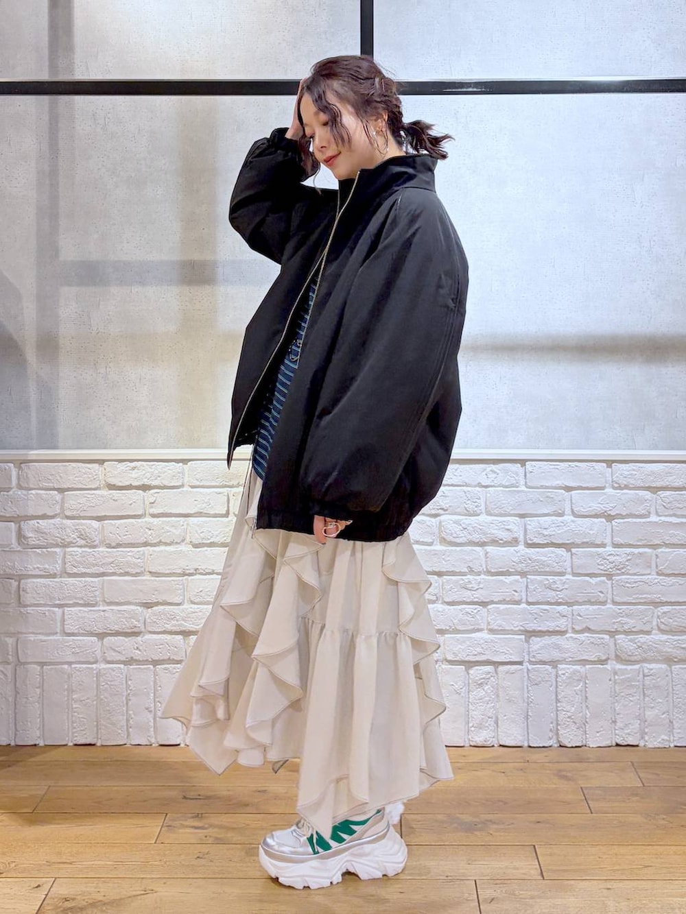 ホワイト系のスニーカー、ベージュ系のスカート、ブラック系のナイロンジャケットを着用したレディースの冬コーディネートの5枚目の写真