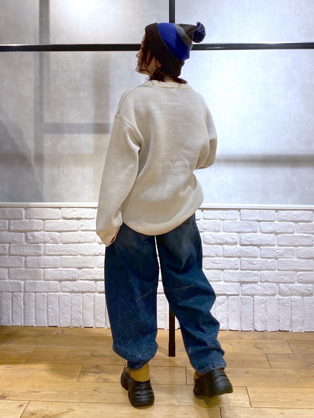 ホワイト系のニット/セーター、ブルー系のデニムパンツ、ブラウン系のブーツを着用したレディースの冬コーディネートの7枚目の写真
