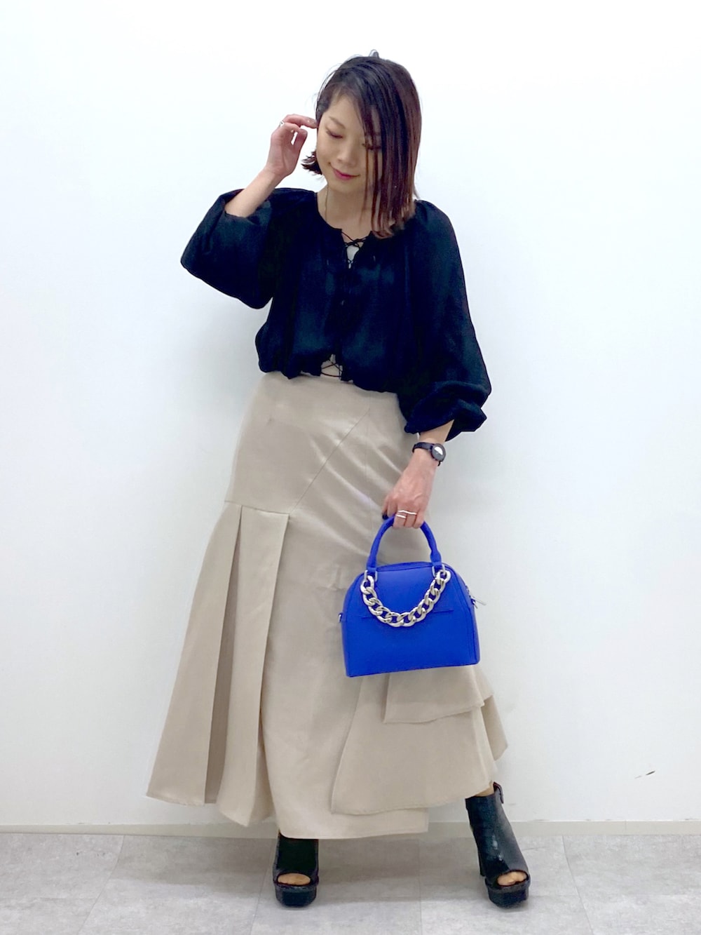 ブラック系のシャツ/ブラウス、ブルー系のショルダーバッグ、ベージュ系のスカートを着用したレディースの春コーディネートの2枚目の写真