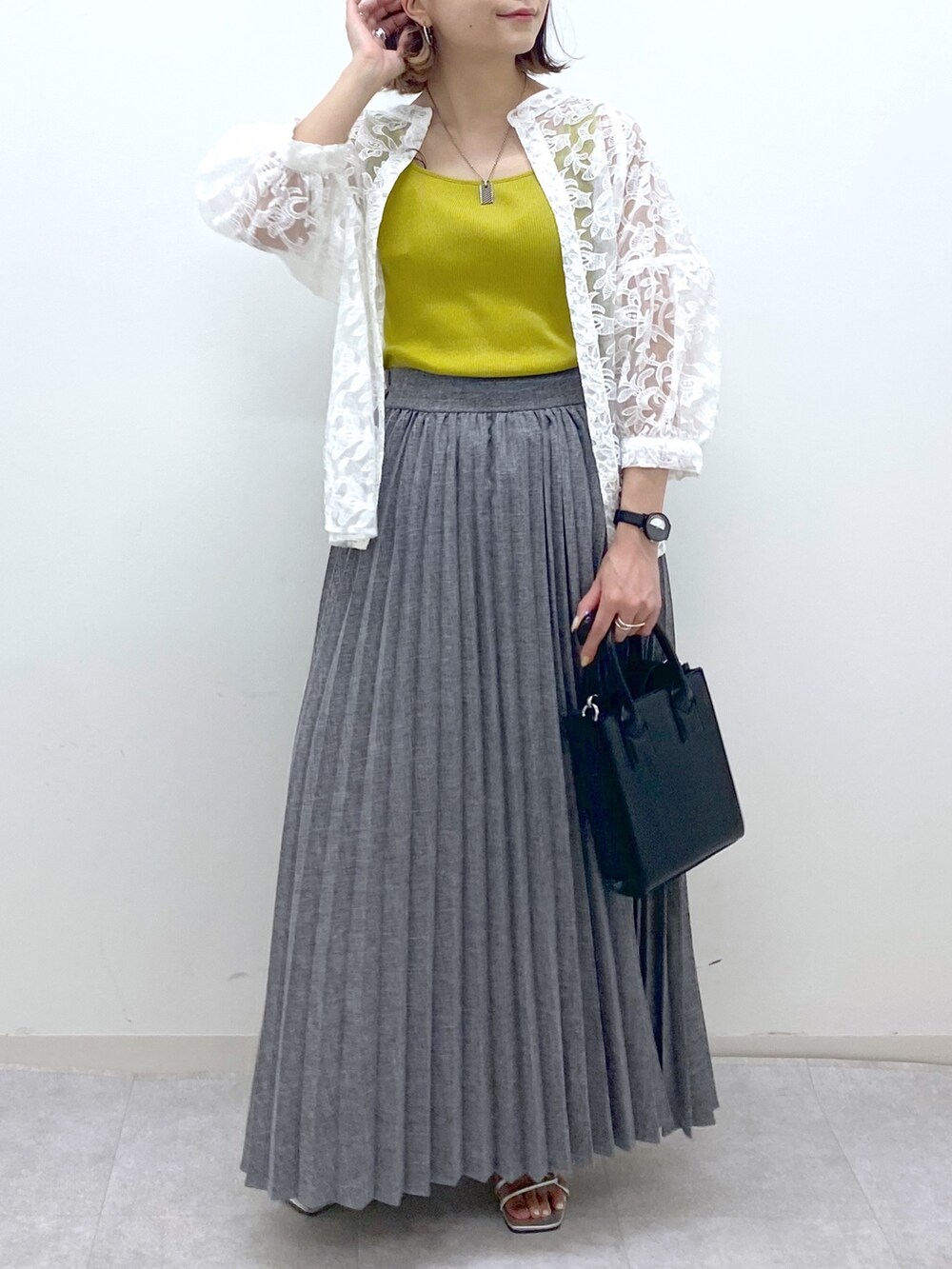 グレー系のスカート、イエロー系のタンクトップ、ホワイト系のトップスを着用したレディースの夏コーディネートの5枚目の写真