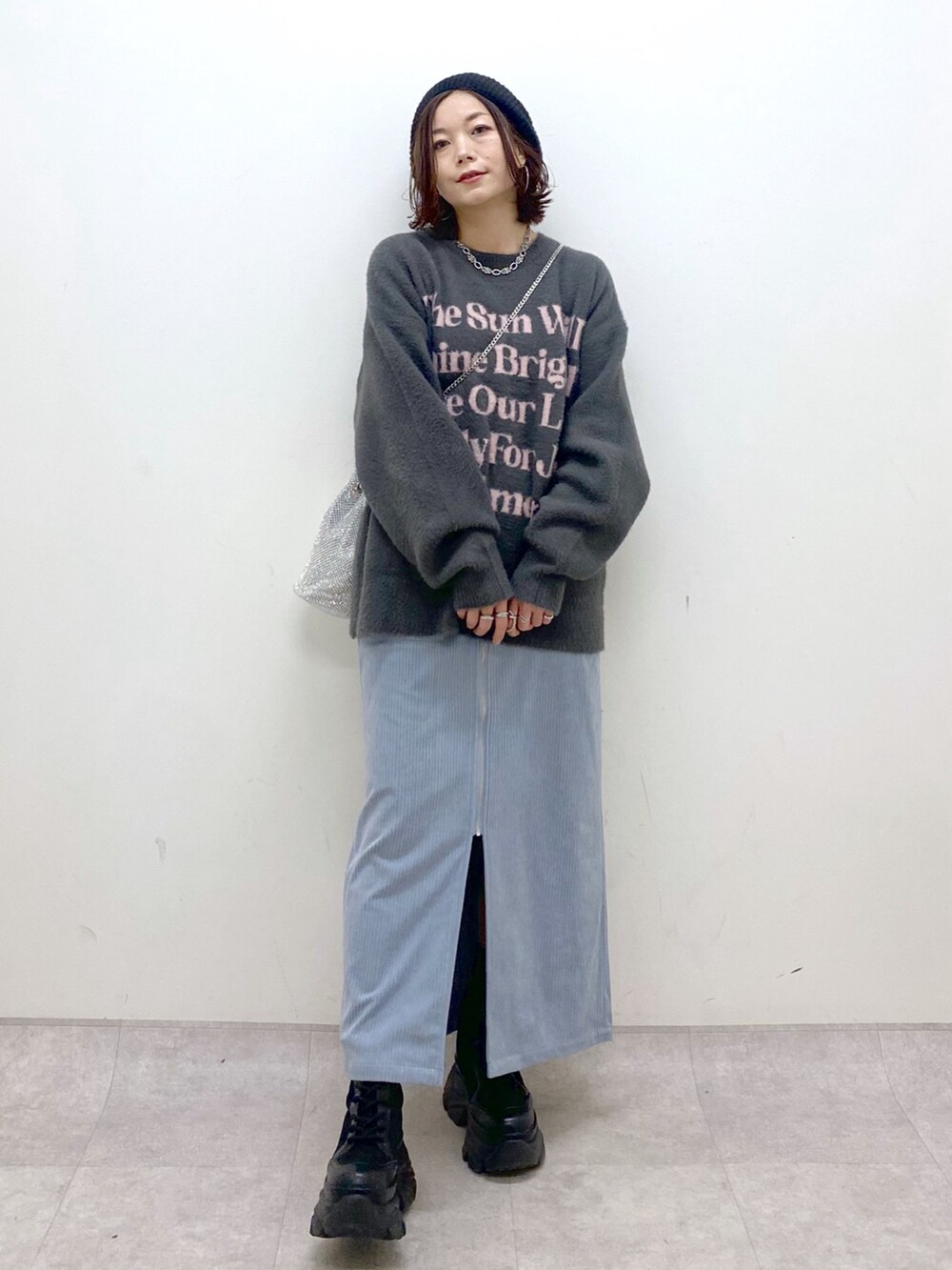 グレー系のニット/セーター、ブルー系のスカート、ブラック系のブーツを着用したレディースの秋コーディネートの8枚目の写真