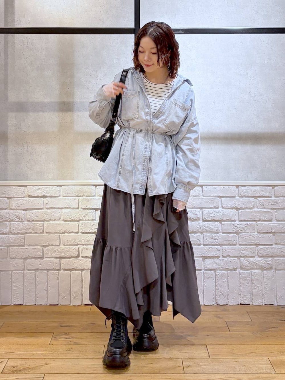 ブラック系のブーツ、ブラック系のショルダーバッグ、グレー系のスカートを着用したレディースの冬コーディネートの4枚目の写真