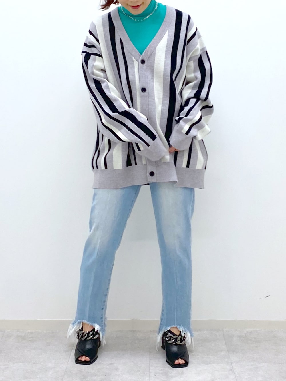 グリーン系のTシャツ/カットソー、ブルー系のデニムパンツ、ブラック系のパンプスを着用したレディースの冬コーディネートの5枚目の写真