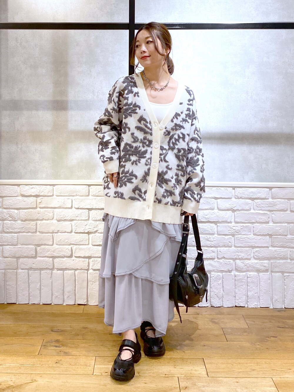 ブラック系のショルダーバッグ、ホワイト系のカーディガン/ボレロ、ホワイト系のキャミソールを着用したレディースの春コーディネートの4枚目の写真