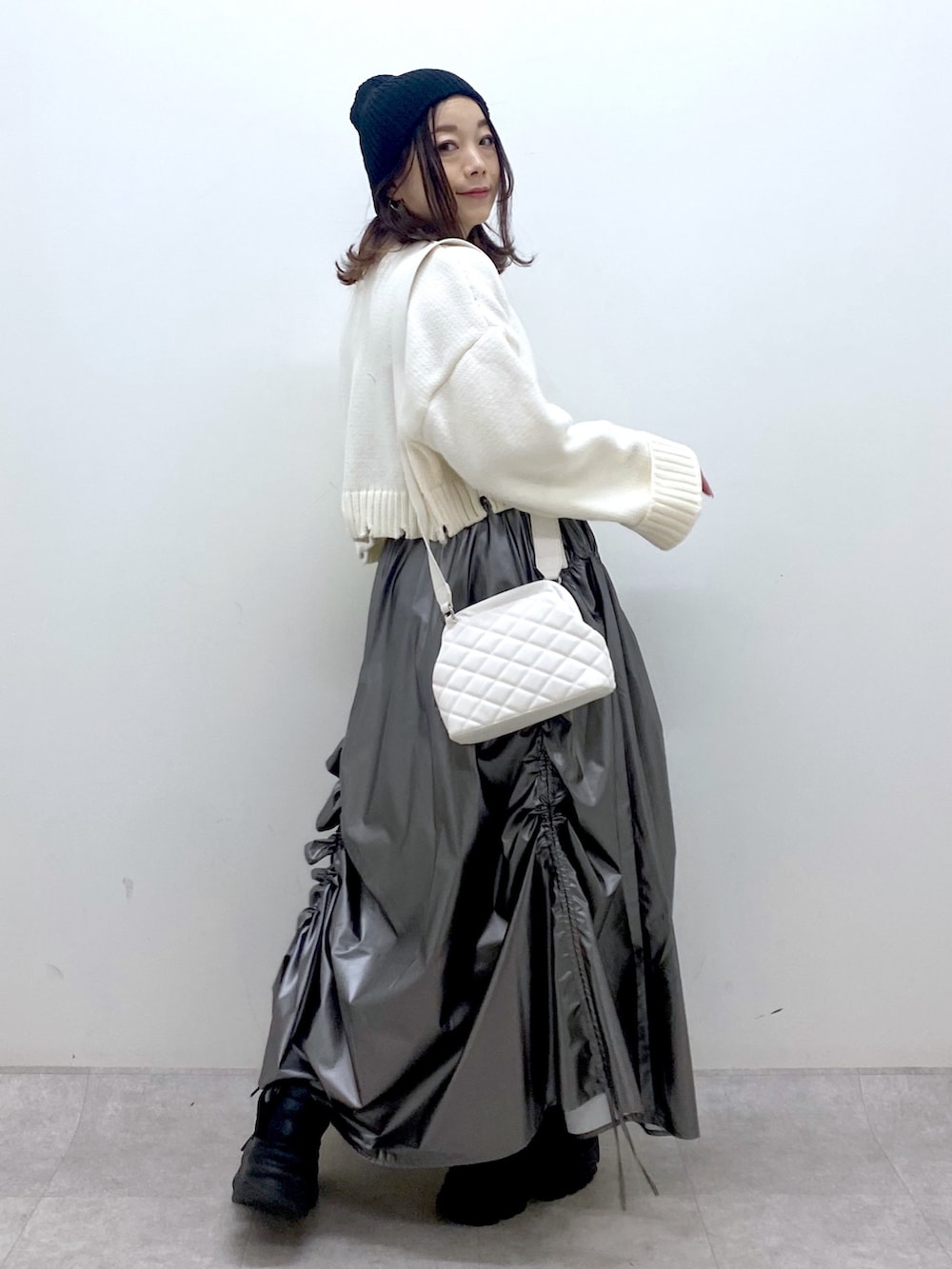 ホワイト系のニット/セーター、シルバー系のスカート、ホワイト系のショルダーバッグを着用したレディースの冬コーディネートの6枚目の写真