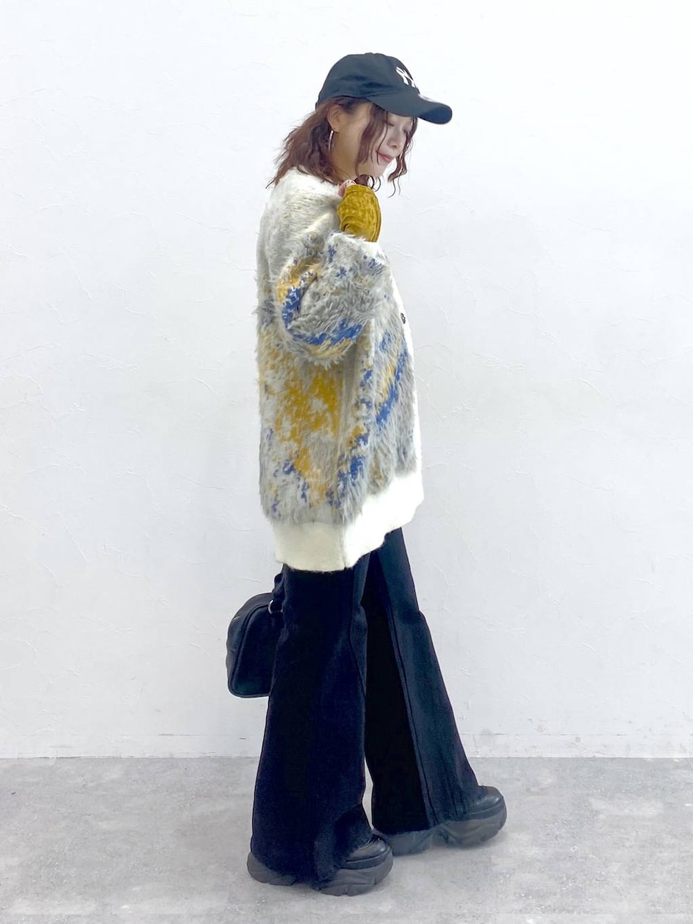 ブラック系のブーツ、ブラック系のボストンバッグ、ホワイト系のカーディガン/ボレロを着用したレディースの秋コーディネートの7枚目の写真