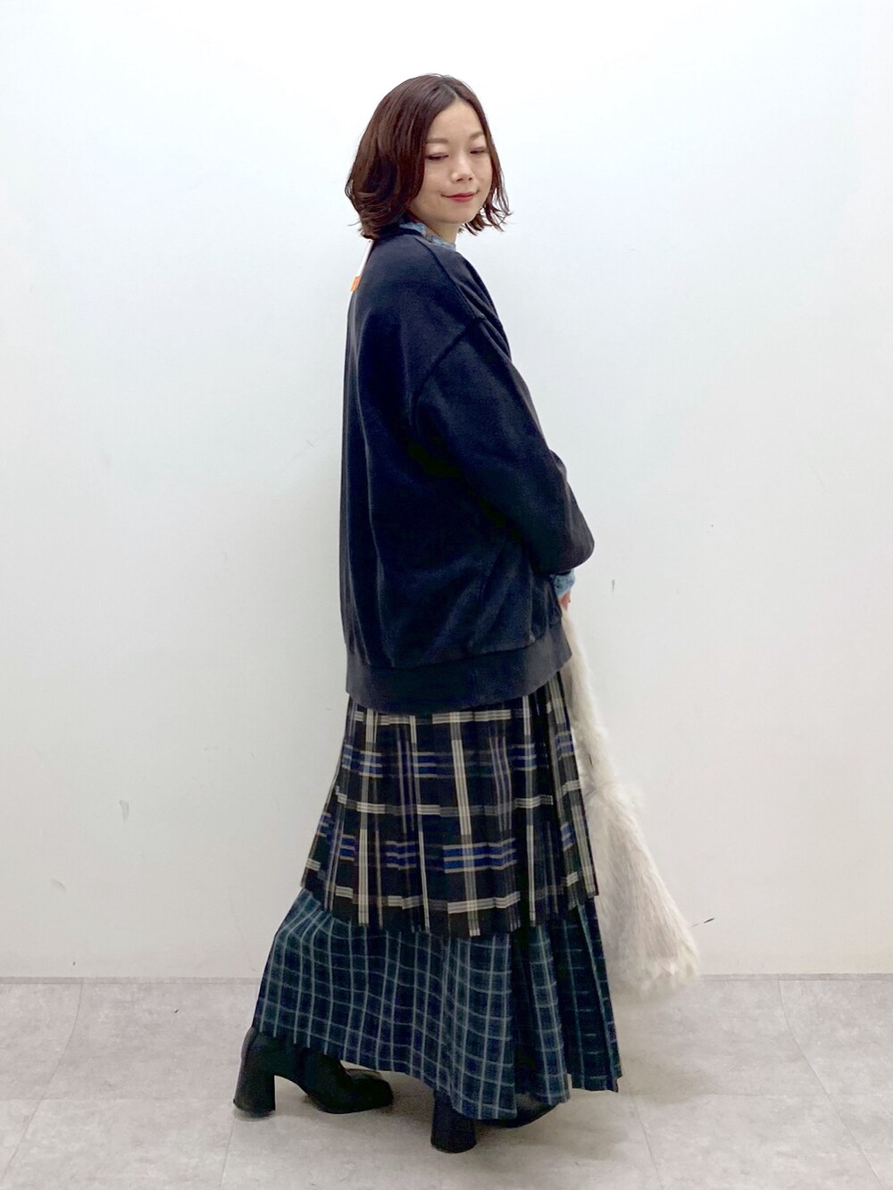 グレー系のスウェット、ブルー系のスカート、ホワイト系のショルダーバッグを着用したレディースの秋コーディネートの5枚目の写真