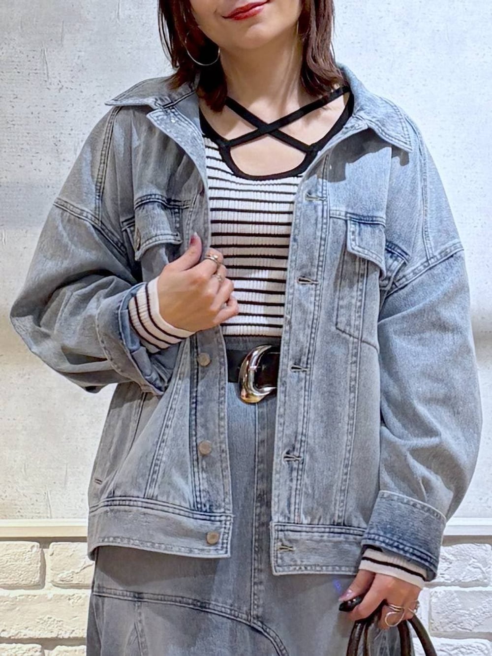 ブルー系のブルゾン、グレー系のショルダーバッグ、ホワイト系のニット/セーターを着用したレディースの春コーディネートの2枚目の写真