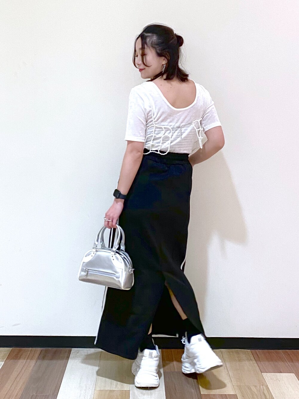 ブラック系のスカート、シルバー系のショルダーバッグ、ホワイト系のスニーカーを着用したレディースの夏コーディネートの8枚目の写真