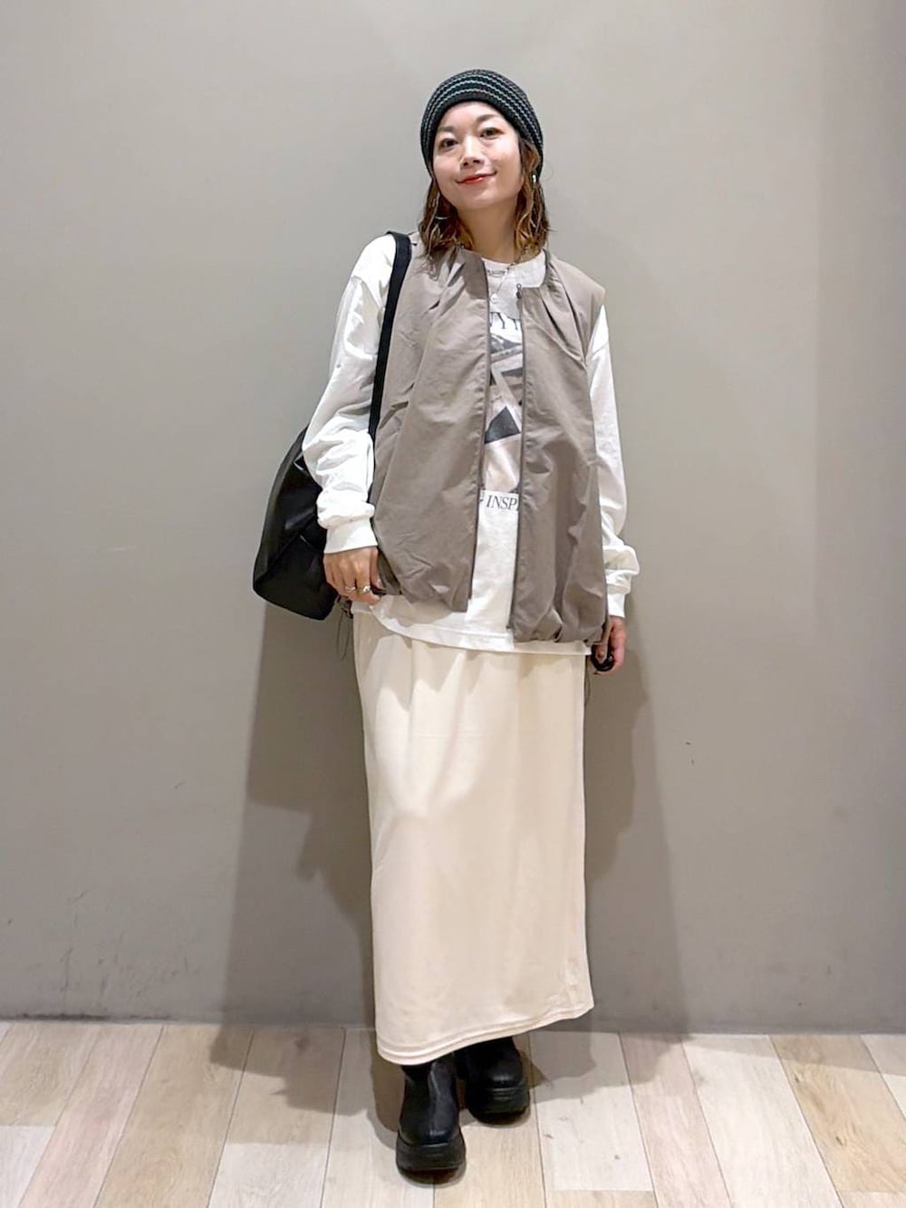 グレー系のベスト、ブラック系のブーツ、ホワイト系のTシャツ/カットソーを着用したレディースの秋コーディネートの4枚目の写真