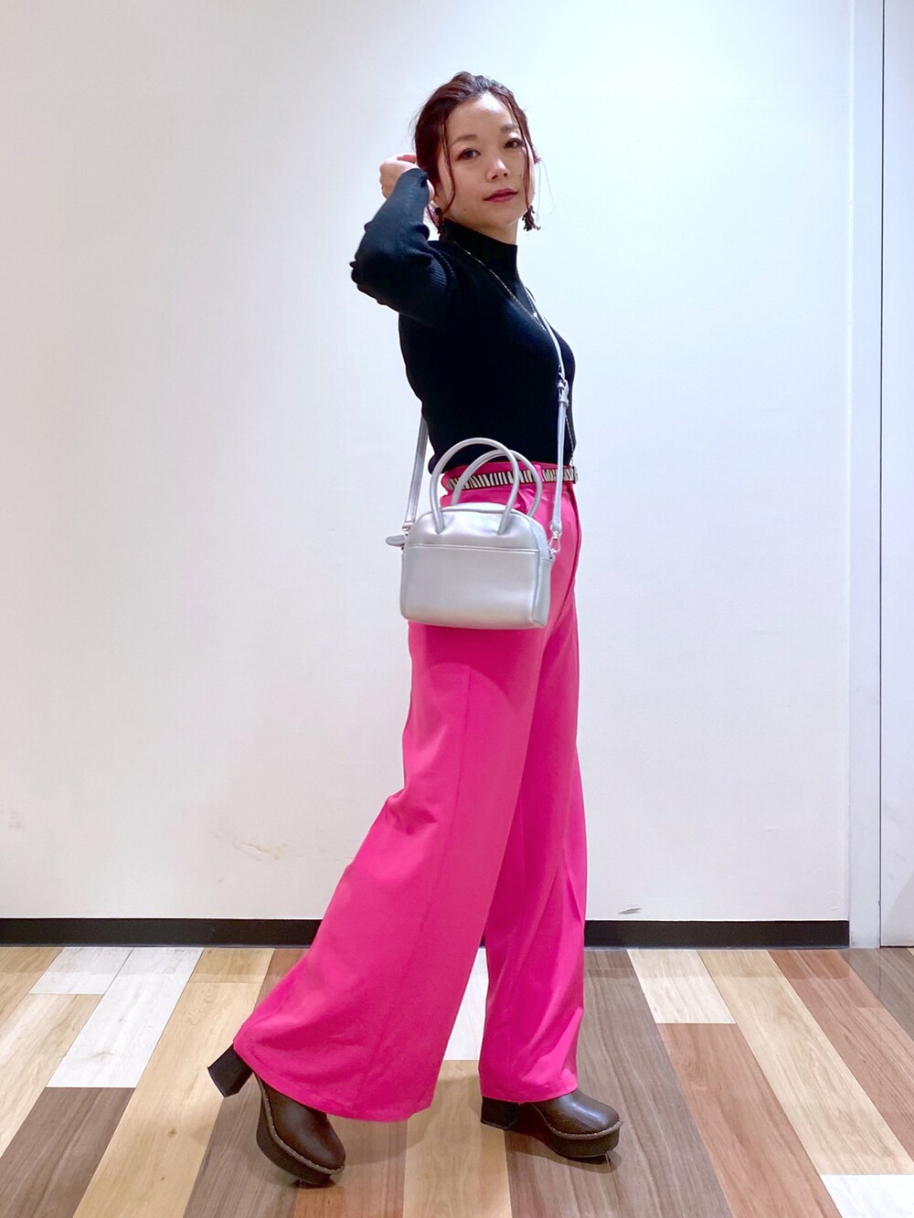 ブラック系のニット/セーター、シルバー系のボストンバッグ、ピンク系のスラックスを着用したレディースの冬コーディネートの3枚目の写真