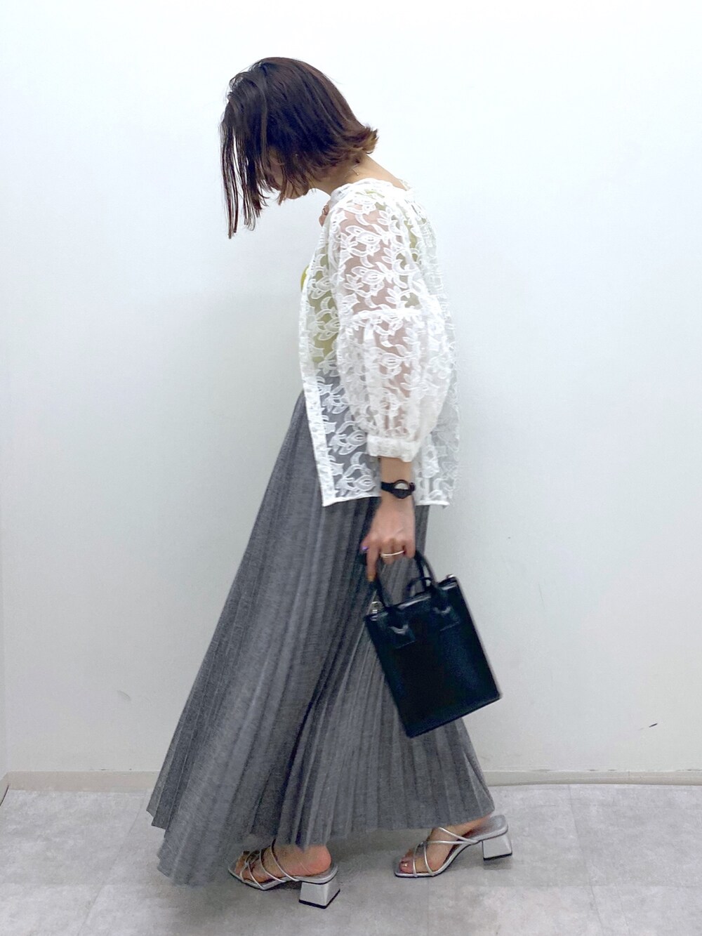 グレー系のスカート、イエロー系のタンクトップ、ホワイト系のトップスを着用したレディースの夏コーディネートの4枚目の写真