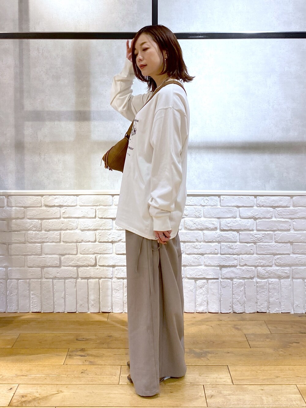 ブラウン系のスラックス、ベージュ系のショルダーバッグ、ブラウン系のパンプスを着用したレディースの春コーディネートの4枚目の写真