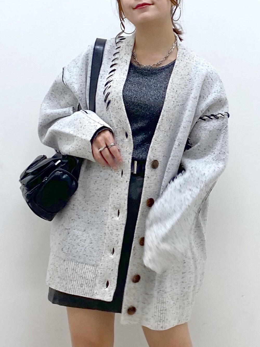 ホワイト系のニット/セーター、シルバー系のTシャツ/カットソー、ブラック系のスカートを着用したレディースの秋コーディネートの2枚目の写真