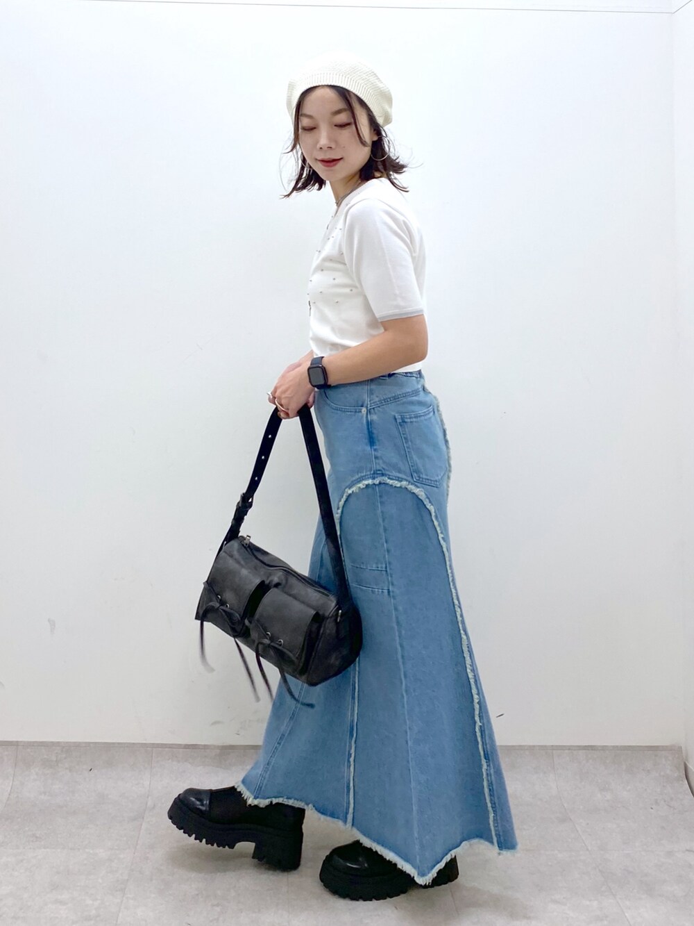 ブルー系のデニムスカート、ホワイト系のニット/セーター、ブラック系のショルダーバッグを着用したレディースの夏コーディネートの8枚目の写真