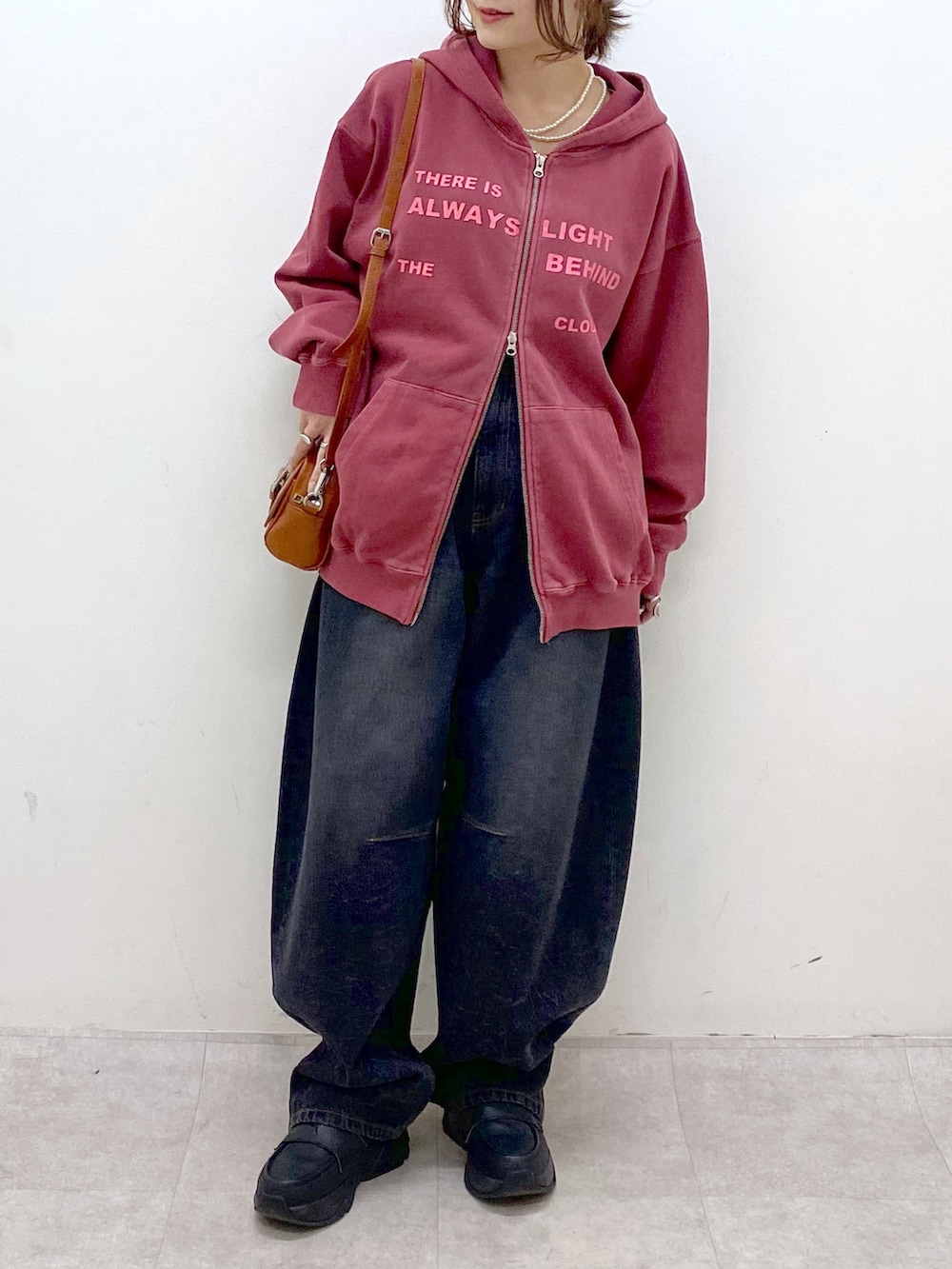 レッド系のスウェット、ブラック系のデニムパンツ、ブラック系のローファーを着用したレディースの冬コーディネートの3枚目の写真