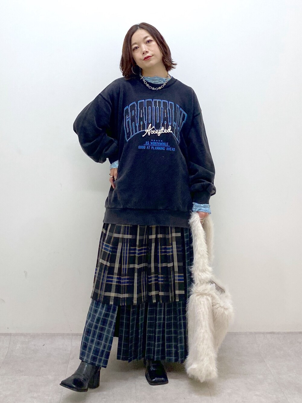 グレー系のスウェット、ブルー系のスカート、ホワイト系のショルダーバッグを着用したレディースの秋コーディネートの9枚目の写真