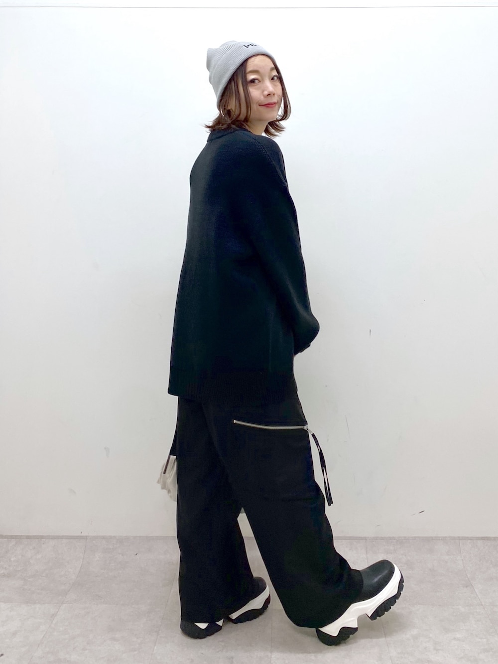 ブラック系のニット/セーター、ブラック系のカーゴパンツ、ホワイト系のショルダーバッグを着用したレディースの冬コーディネートの5枚目の写真