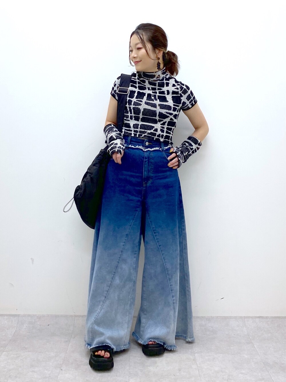 ブルー系のデニムパンツ、ブラック系のニット/セーター、ブラック系のショルダーバッグを着用したレディースの夏コーディネートの2枚目の写真