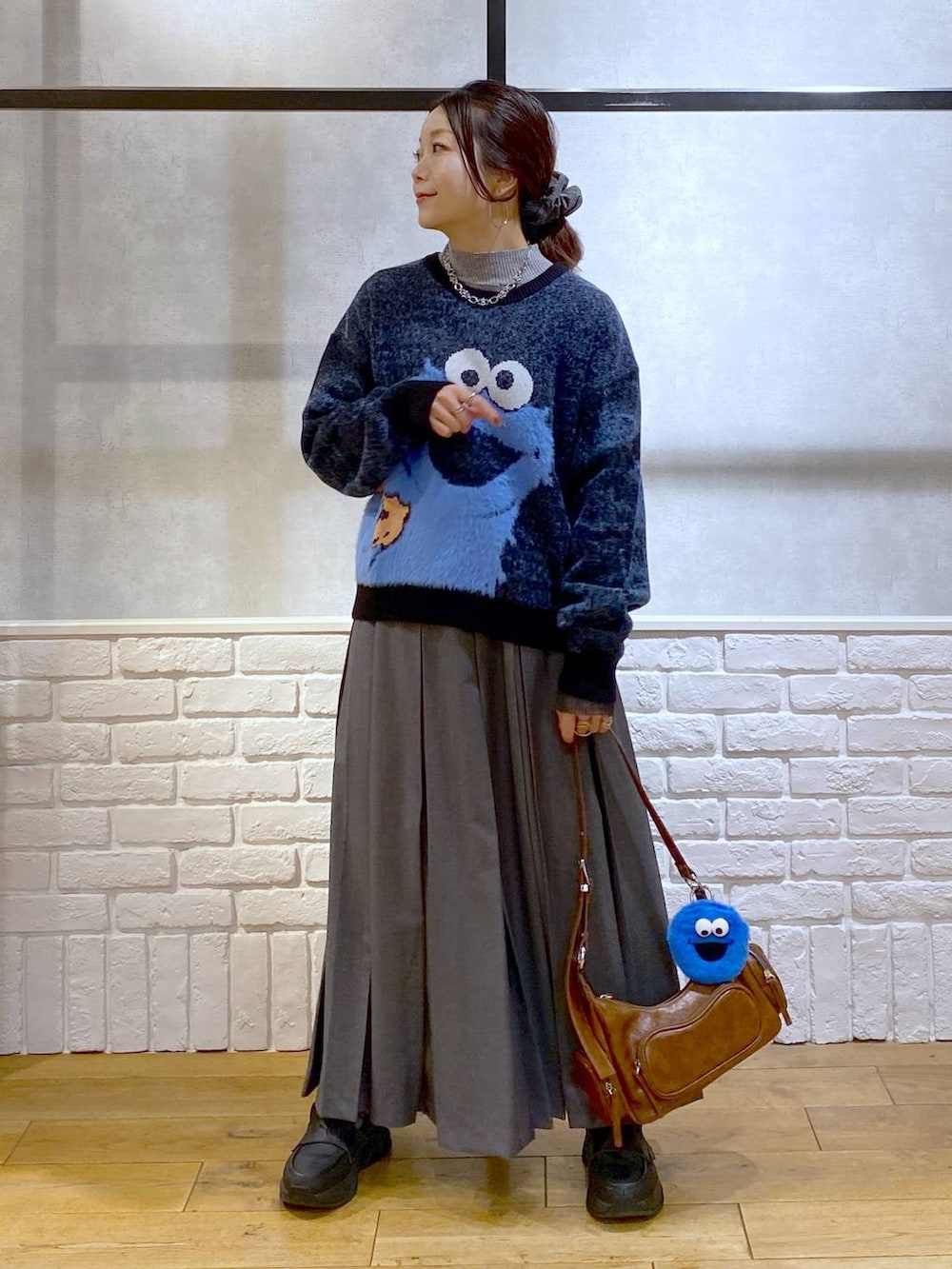 ブラック系のローファー、グレー系のスカート、ブラウン系のショルダーバッグを着用したレディースの冬コーディネートの5枚目の写真