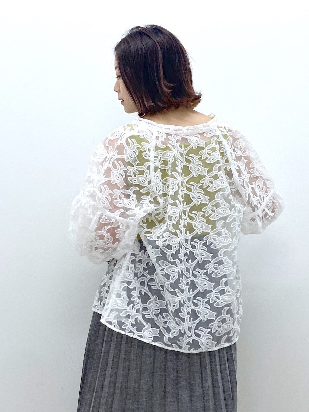 グレー系のスカート、イエロー系のタンクトップ、ホワイト系のトップスを着用したレディースの夏コーディネートの3枚目の写真