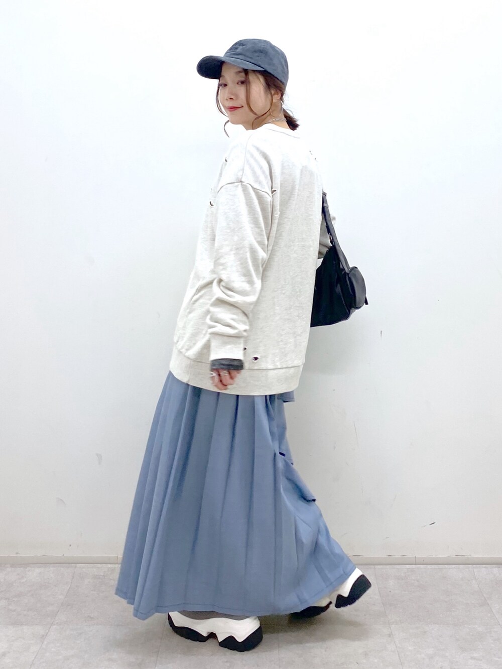 ブラック系のショルダーバッグ、ブルー系のスカート、グレー系のブーツを着用したレディースの秋コーディネートの8枚目の写真