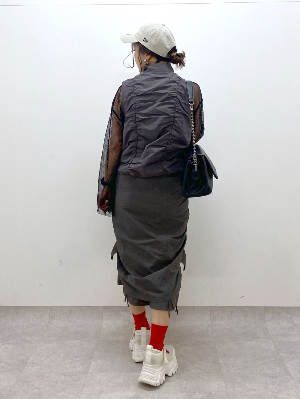 グレー系のスカート、ブラック系のショルダーバッグ、ブラック系のTシャツ/カットソーを着用したレディースの春コーディネートの6枚目の写真