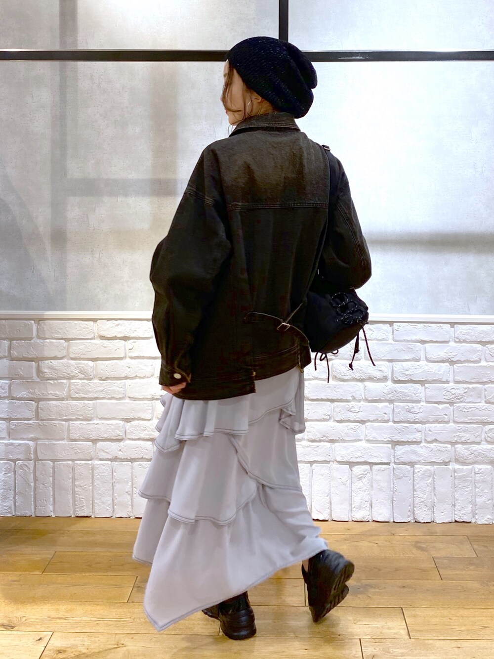 ブラック系のデニムジャケット、グレー系のスカート、ブラック系のスニーカーを着用したレディースの春コーディネートの6枚目の写真