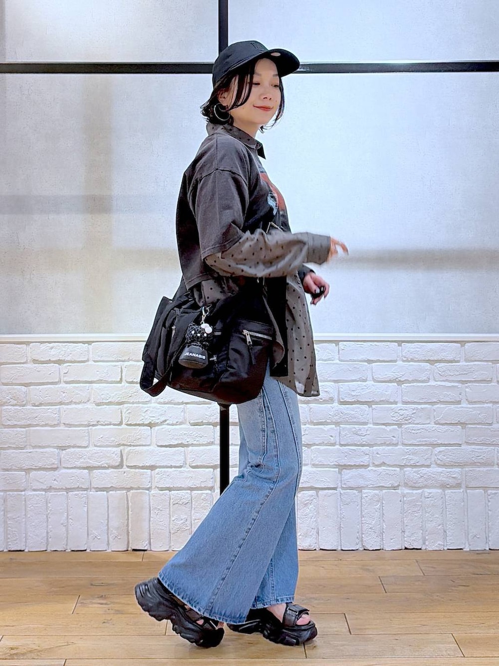 ブルー系のデニムパンツ、ブラック系のボストンバッグ、ブラック系のサンダルを着用したレディースの春コーディネートの5枚目の写真
