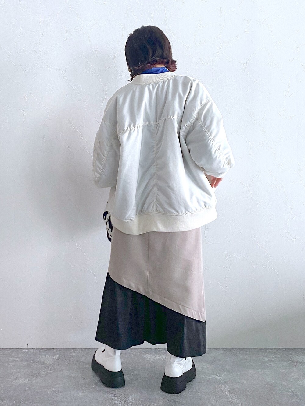 ホワイト系のMA-1、ベージュ系のスカート、ホワイト系のブーツを着用したレディースの夏コーディネートの3枚目の写真