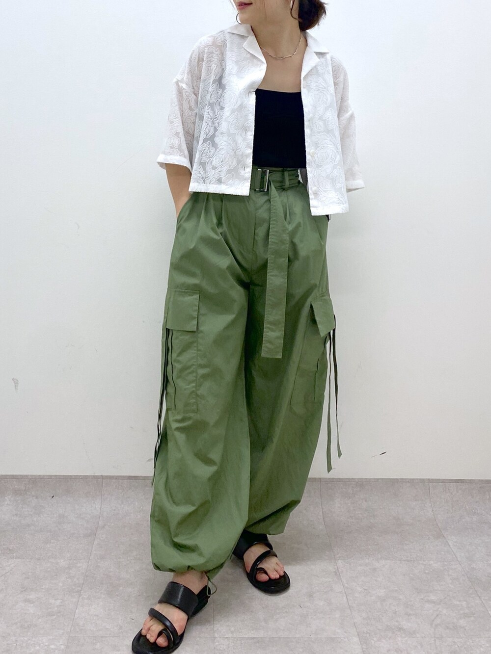 グリーン系のカーゴパンツ、ブラック系のサンダル、ブラック系のトップスを着用したレディースの夏コーディネートの4枚目の写真