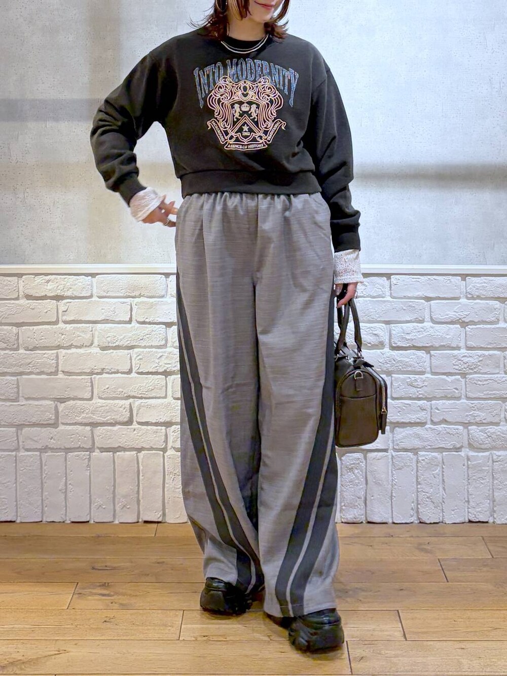 ブラック系のスニーカー、グレー系のスウェット、ブラック系のショルダーバッグを着用したレディースの冬コーディネートの3枚目の写真