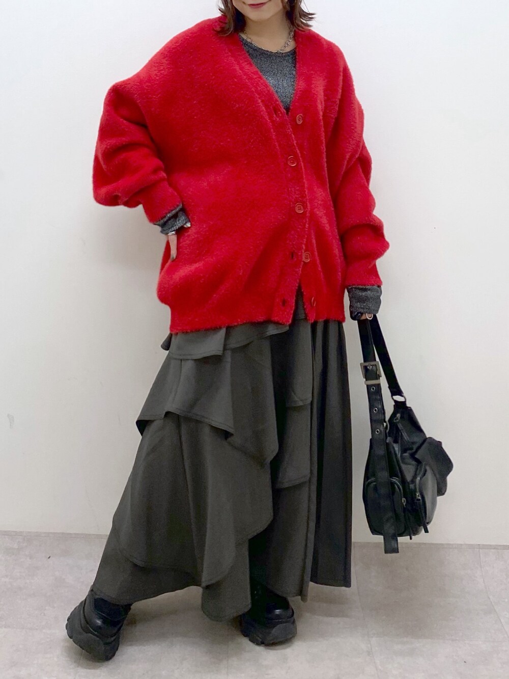 レッド系のカーディガン/ボレロ、シルバー系のTシャツ/カットソー、ブラウン系のスカートを着用したレディースの秋コーディネートの3枚目の写真