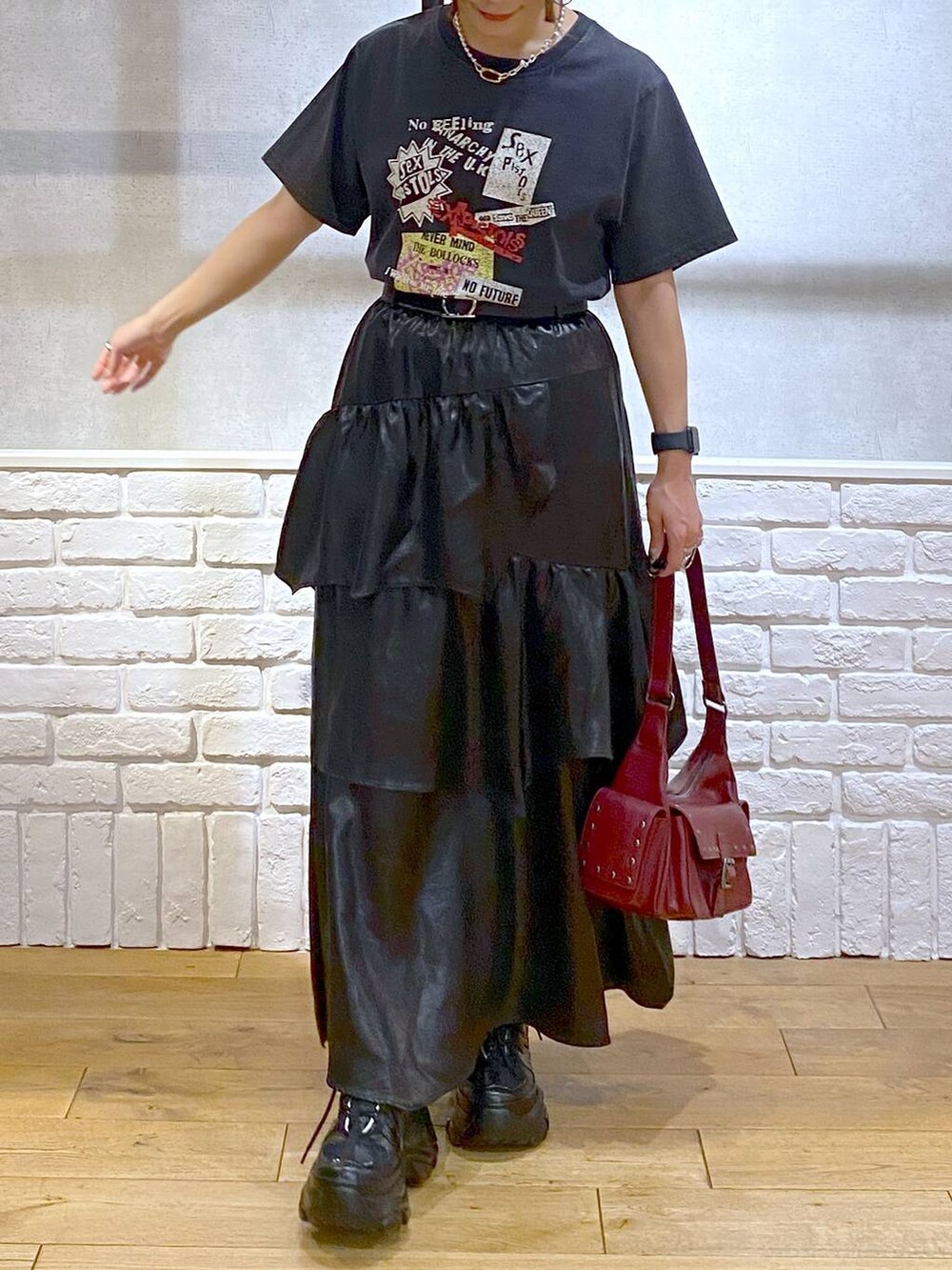 ブラック系のスニーカー、レッド系のショルダーバッグ、ブラック系のスカートを着用したレディースの夏コーディネートの3枚目の写真