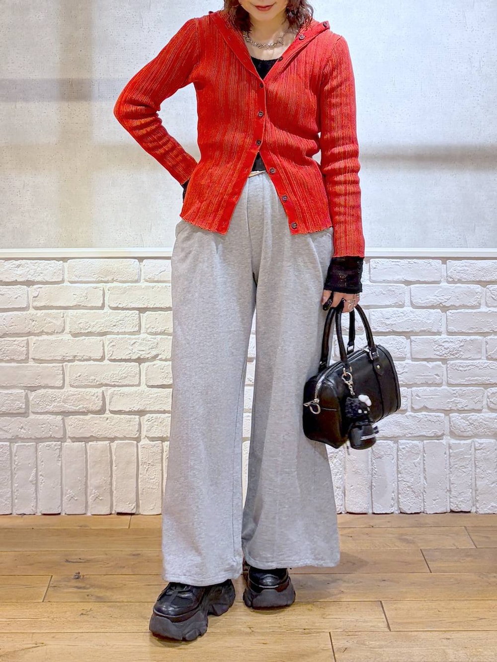 ブラック系のスニーカー、ブラック系のボストンバッグ、レッド系のカーディガン/ボレロを着用したレディースの春コーディネートの3枚目の写真