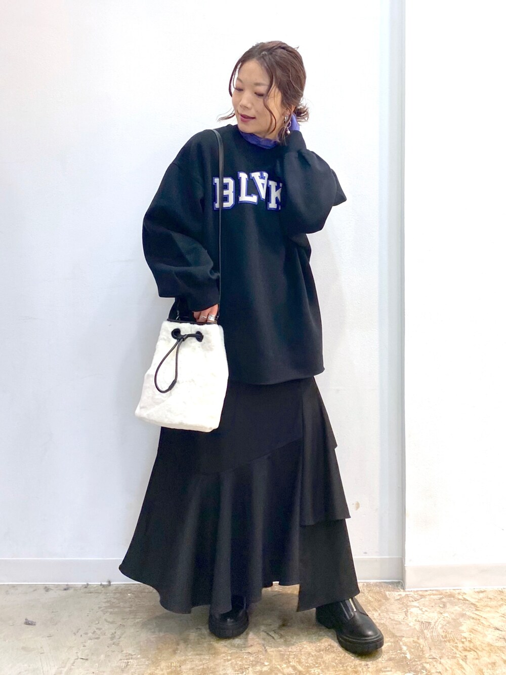 ブラック系のスカート、ブラック系のブーツ、ホワイト系のショルダーバッグを着用したレディースの秋コーディネートの2枚目の写真