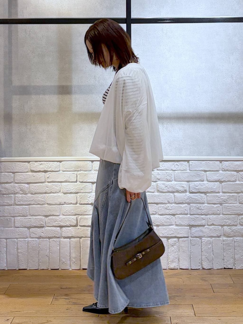 ブラウン系のハンドバッグ、ホワイト系のニット/セーター、ブラック系のサンダルを着用したレディースの春コーディネートの5枚目の写真