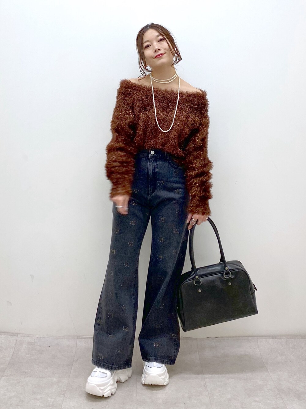 ブラウン系のニット/セーター、ブラック系のボストンバッグ、ホワイト系のスニーカーを着用したレディースの冬コーディネートの4枚目の写真