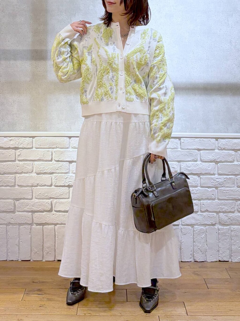 グレー系のショルダーバッグ、ブラウン系のサンダル、ホワイト系のスカートを着用したレディースの冬コーディネートの3枚目の写真