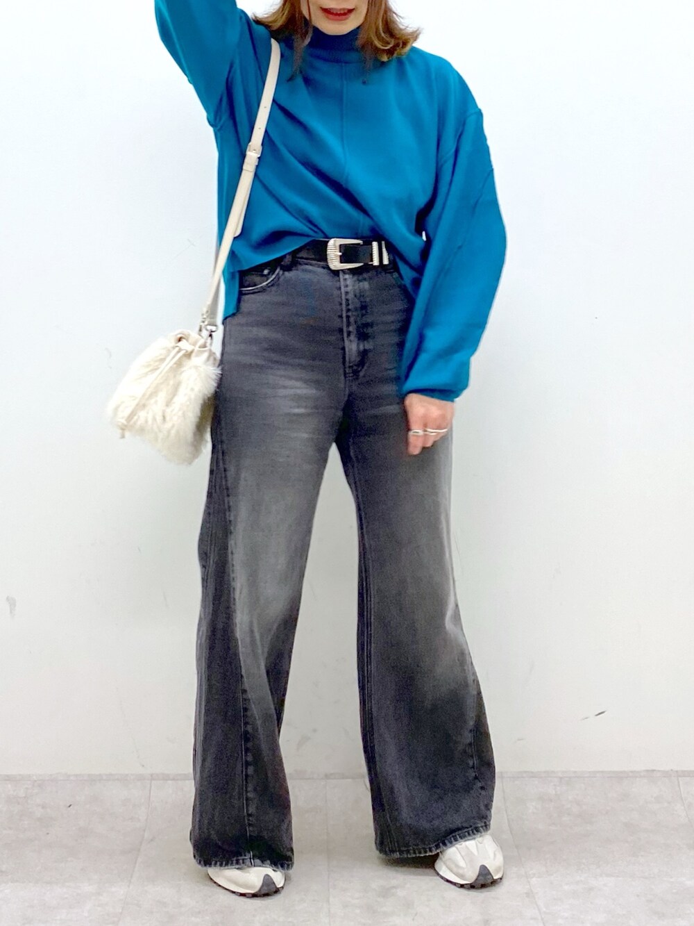 ブラック系のデニムパンツ、ホワイト系のショルダーバッグ、ブルー系のニット/セーターを着用したレディースの秋コーディネートの7枚目の写真