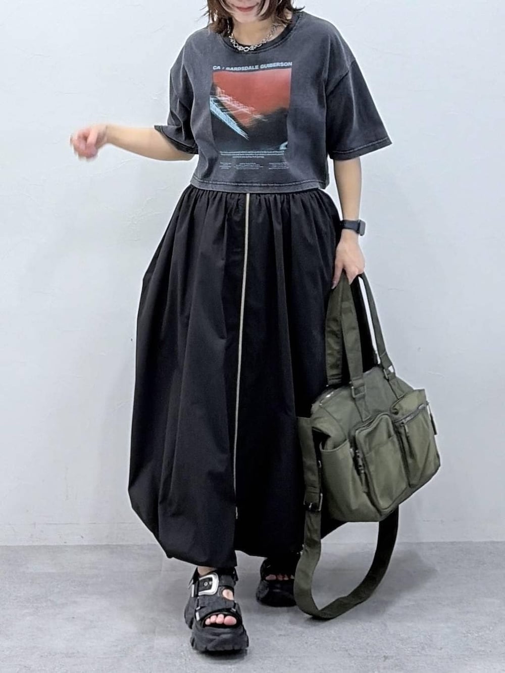 グリーン系のボストンバッグ、ブラック系のサンダル、ブラック系のスカートを着用したレディースの春コーディネートの2枚目の写真