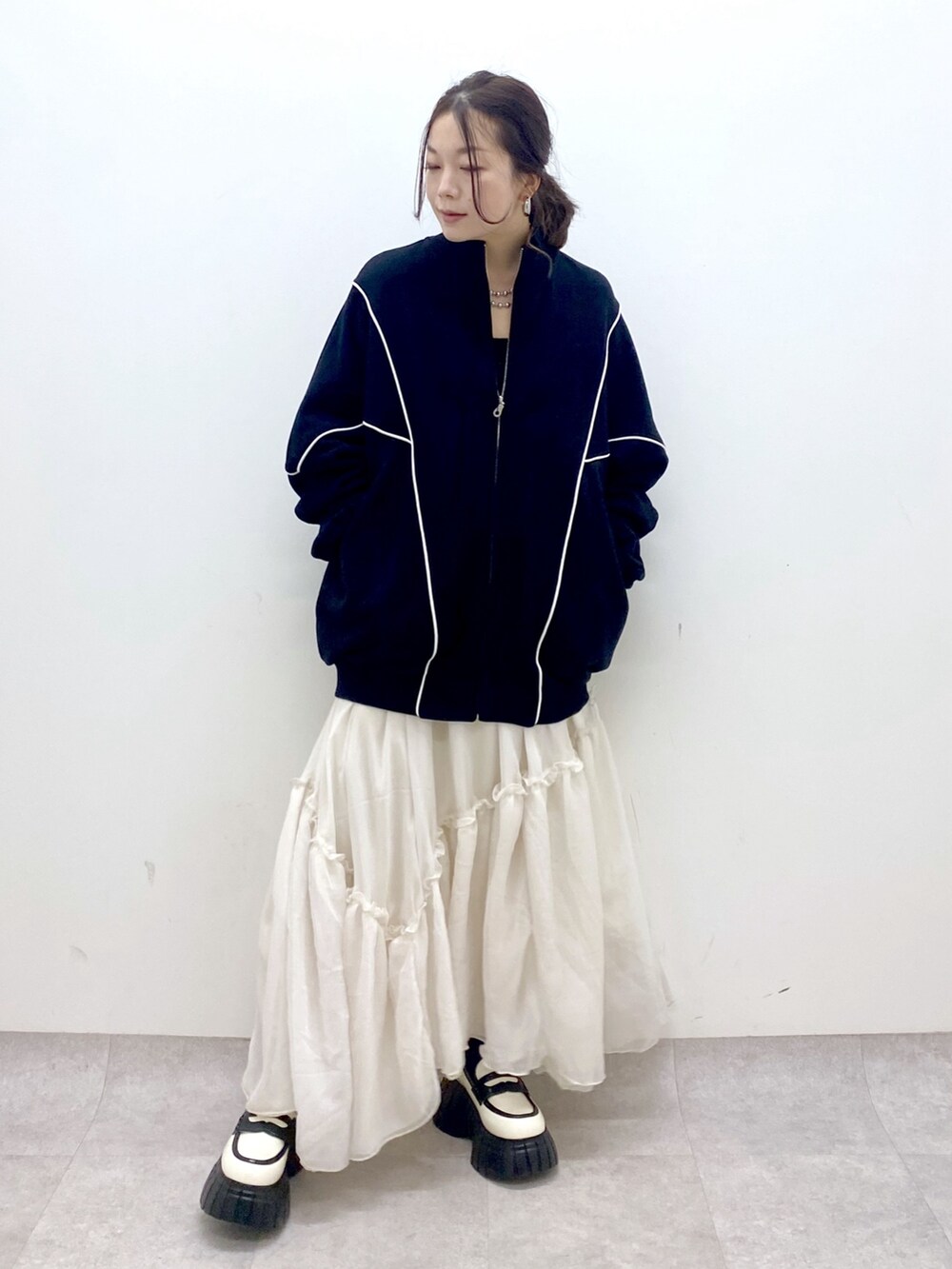 ブラック系のスウェット、ホワイト系のスカート、ホワイト系のローファーを着用したレディースの春コーディネートの9枚目の写真