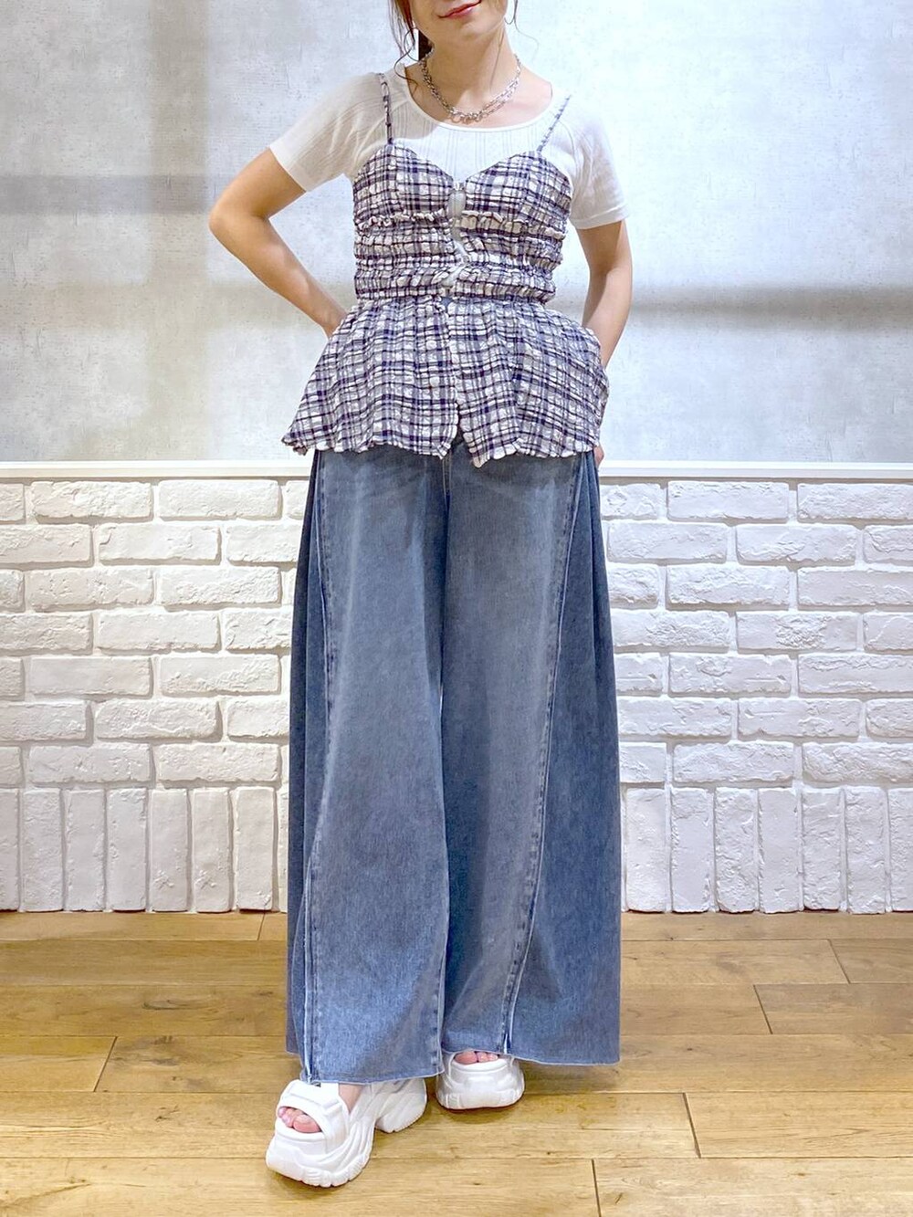 ホワイト系のサンダル、ブルー系のデニムパンツ、ブルー系のキャミソールを着用したレディースの夏コーディネートの3枚目の写真