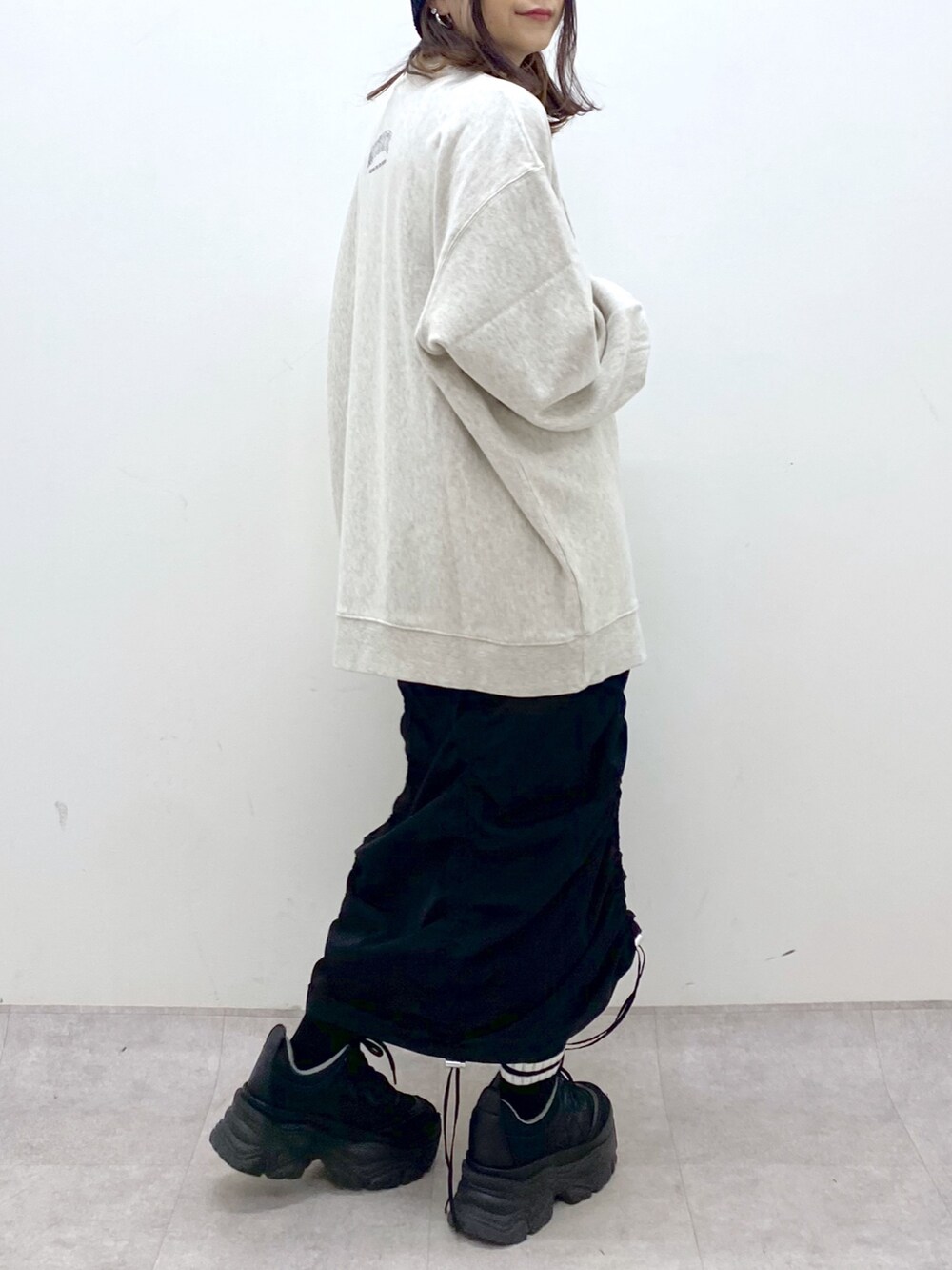 ベージュ系のスウェット、ブラック系のワンピース、ブラック系のスニーカーを着用したレディースの冬コーディネートの7枚目の写真