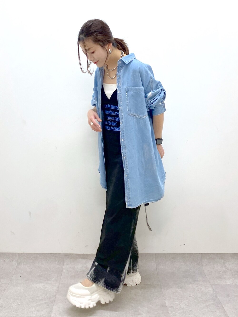 ブラック系のデニムパンツ、ホワイト系のスニーカー、ブラック系のワンピースを着用したレディースの春コーディネートの8枚目の写真