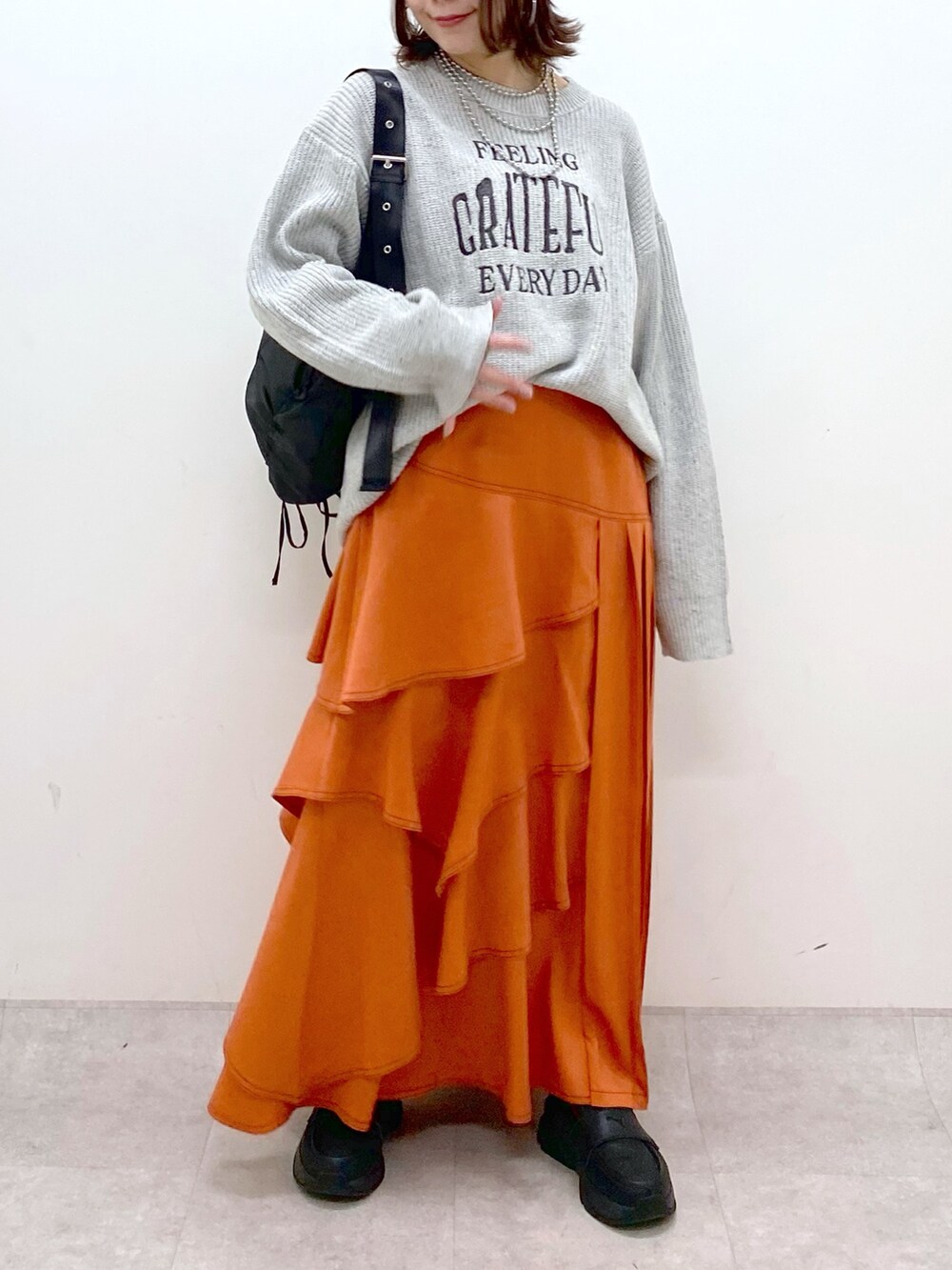 グレー系のニット/セーター、オレンジ系のスカート、ブラック系のローファーを着用したレディースの冬コーディネートの3枚目の写真