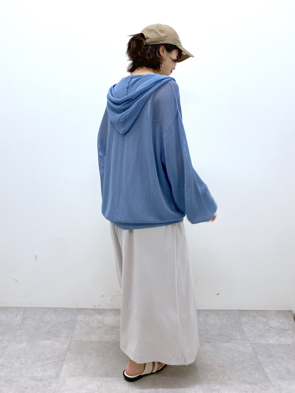 ベージュ系のジャンパースカート、ブルー系のニット/セーター、ブラック系のキャミソールを着用したレディースの夏コーディネートの2枚目の写真